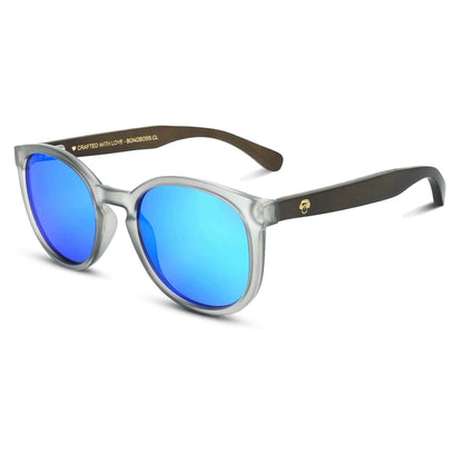 anteojos redondos de plástico reciclado y varillas de madera natural sustentable con lentes de color azul espejado. Polarizadas y forma redonda. La gafa es color transparente #color_espejado-azul