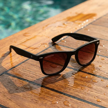 Lentes sol Acacio RPET polarizados UV400 sobre madera teca con agua fresca Bonoboss #color_rojo