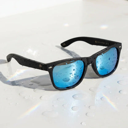 Lentes sol Acacia Dark polarizados UV400 sobre superficie con agua y luz natural Bonoboss #color_sky