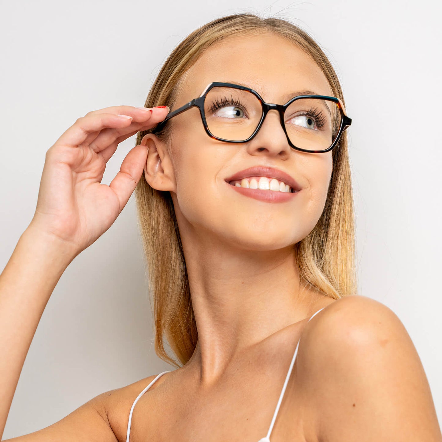 una mujer de pelo rubio y de cara ovalada utilizando unos armazones o anteojos opticos Bonoboss de color carey sonriendo hacia la parte superior derecha del cuadro  lentes opticos cuadrados carey mujer cara redonda receta multifocal bifocal adelgazado filtro azul..jpg #color_carey