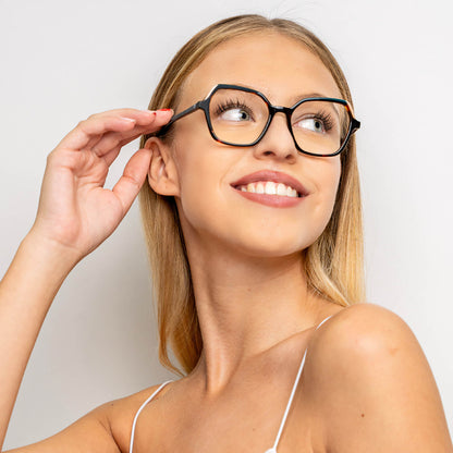 una mujer de pelo rubio y de cara ovalada utilizando unos armazones o anteojos opticos Bonoboss de color carey sonriendo hacia la parte superior derecha del cuadro  lentes opticos cuadrados carey mujer cara redonda receta multifocal bifocal adelgazado filtro azul..jpg #color_carey