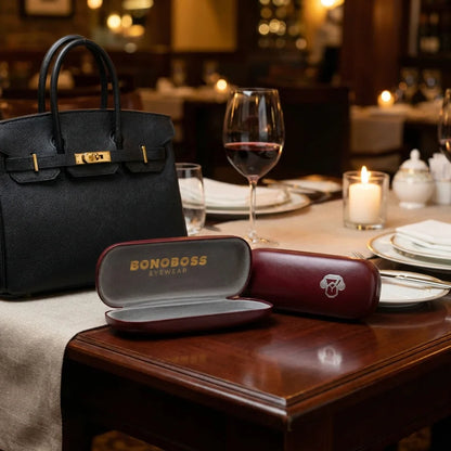 Estuche almeja para lentes burdeo en mesa de restaurante Bonoboss #color_burdeo