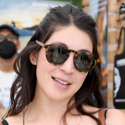 mujer de cara ovalada con anteojos de sol polarizados de plastico reciclado y patas de madera natural #color-marco_carey