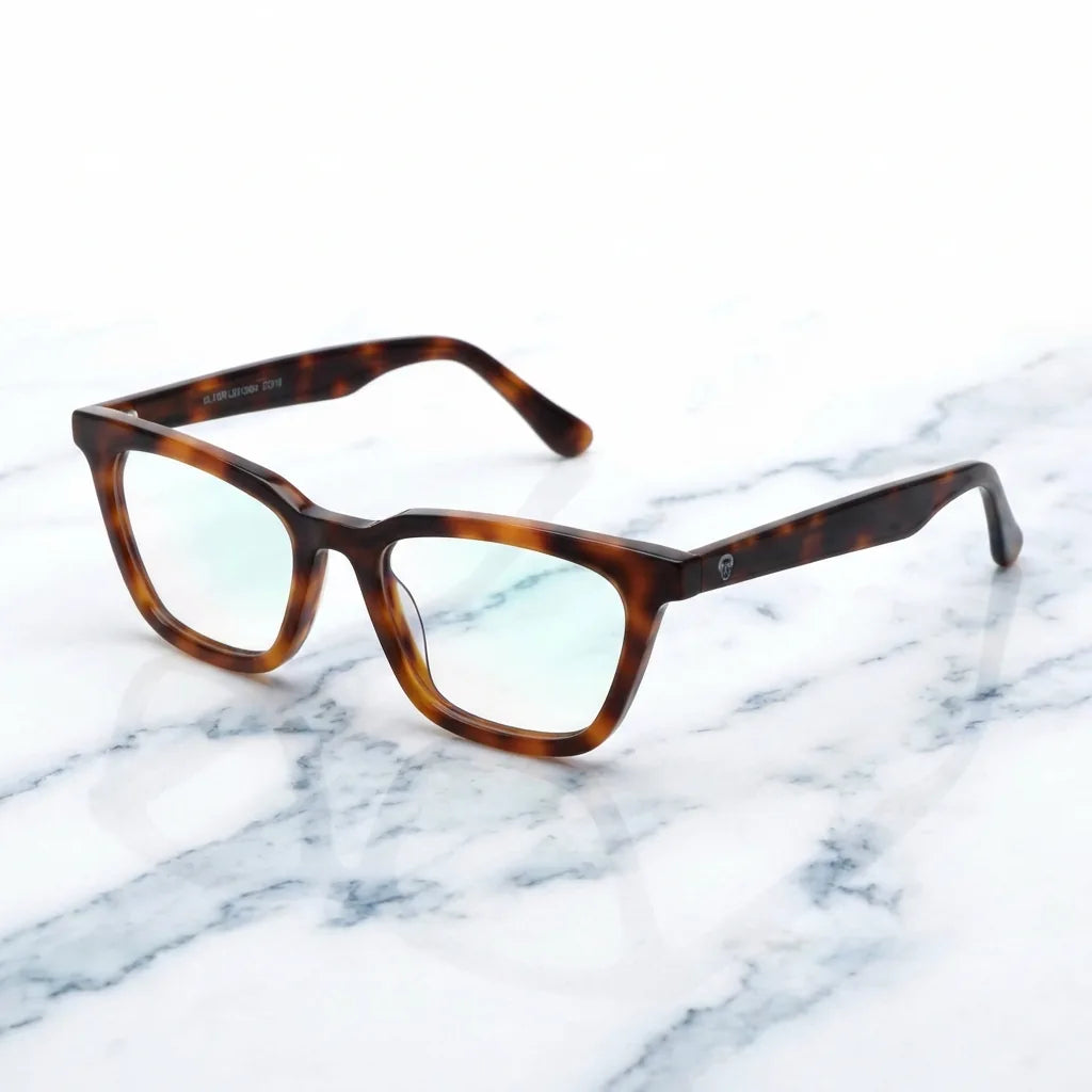 Lentes ópticos Oliver Carey sobre mármol blanco elegante armazón premium Bonoboss #editorial_armazon #color_carey